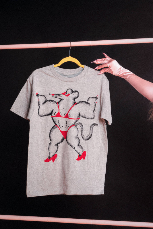 The front of a light gray, oversized t-shirt with a graphic design of a buff rat in a red bikini with red heels and red sunglasses, a little red nose, and red painted nails. Shirt is on a hanger against a black background.