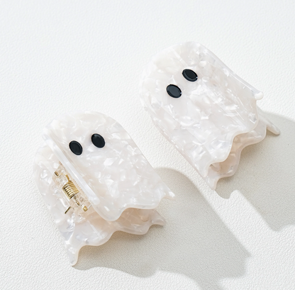 Two ghost-shaped hair claw clips made of textured, translucent white resin with black eyes, displayed on a clean white background.